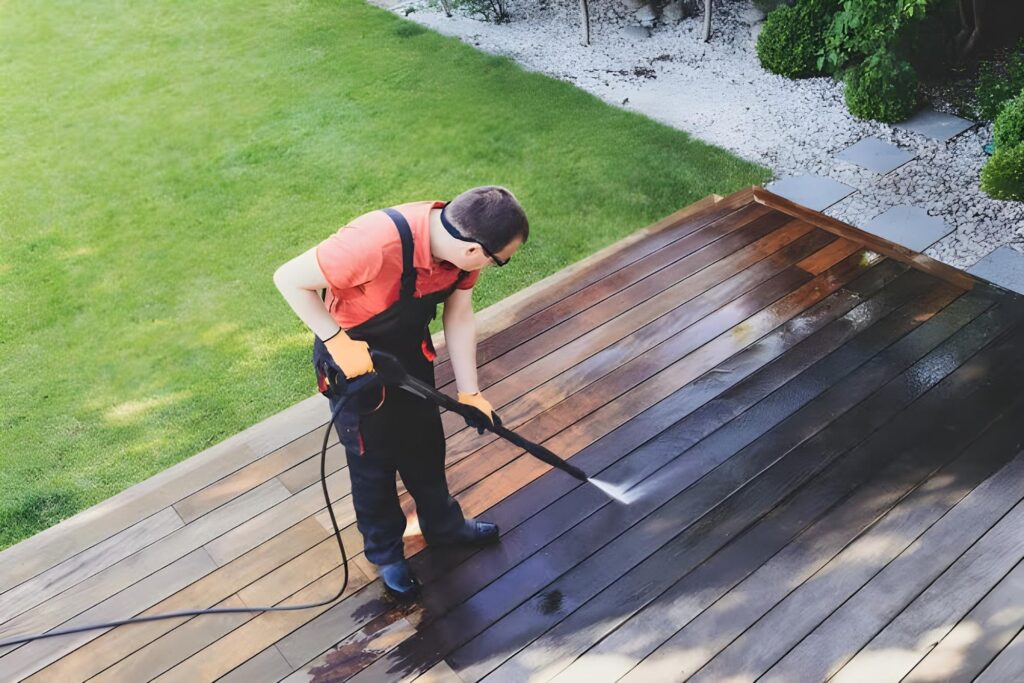 man using a pressure washer to clean patio deck