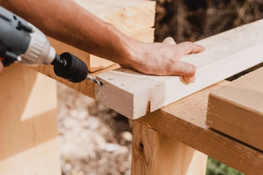 image of a carpenter drilling a hole on a piece of wood