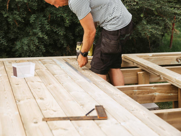 Man building a wooden patio deck outdoors in his garden Working and buidling under contstruction. Home improvement.