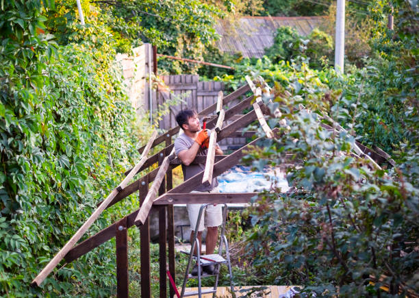 Man building wooden roof outdoors standing on ladder.