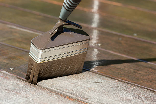 Close-up of brush with terrace oil during maintenance of teak terrace.