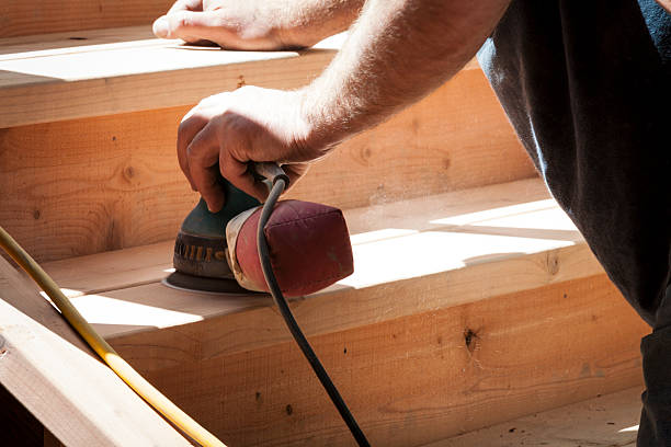 Man sanding staircase of redwood with orbital sander